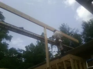 Carpenter setting a ridge beam over a new addition frame — Ice Dam Removal by Roofing Brothers in Belt