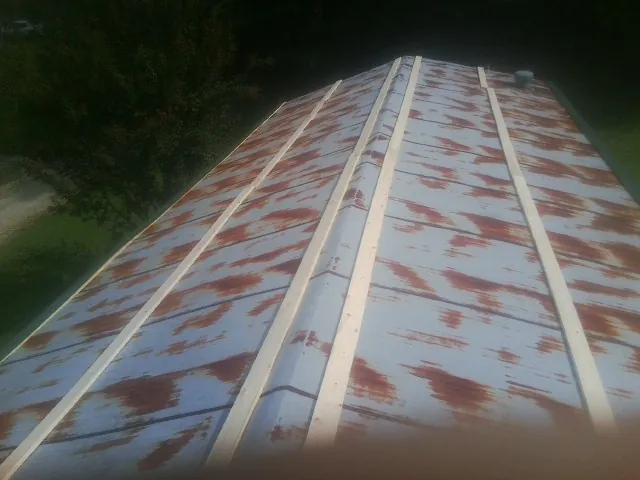 Rusted metal roof panels with new wood purlins before replacement — Storm Damage Roof Repair in Belt by Roofing Brothers