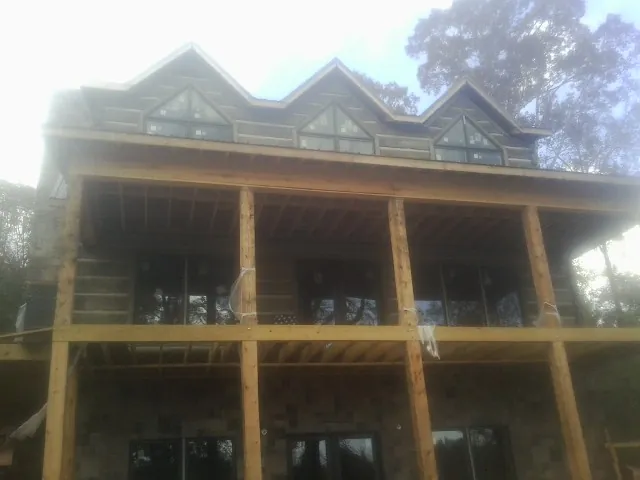 Dormers and porch framing on a large log home under construction — Roof Coating work by our crew in Belt