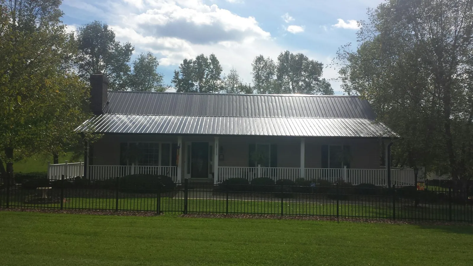 Gray metal roof on a brick ranch with a full width front porch — Gutter Guard Installation work by our crew in Belt